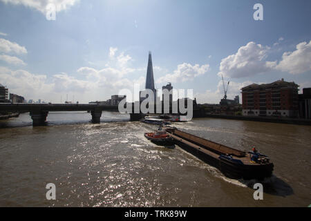 Barge, die Cory Umwelt, das größte Schiff auf der Themse, fließt zwischen Cannon Street Railway Bridge und die Southwark Bridge über die Themse, mit Schleppern und Shard im Hintergrund Stockfoto