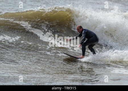 Im mittleren Alter Surfer zeigt seinen Stil. Rest Bay Porthcawl, Großbritannien. Stockfoto