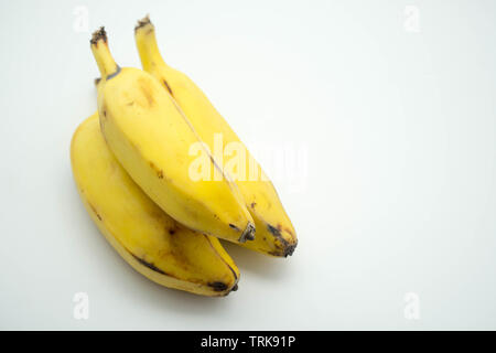Drei kurze reife Bananen auf einander stapeln auf einem isolierten weißen Hintergrund Stockfoto