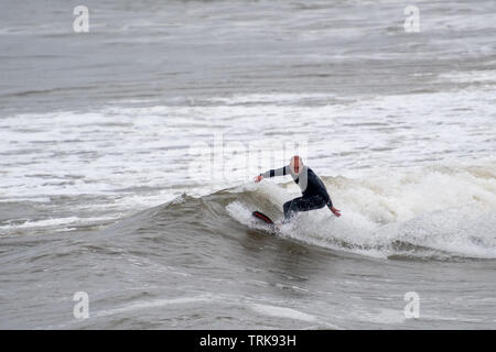 Sogar ein wenig Regen nicht aufhört ein im mittleren Alter Surfer von sich selbst genießen. Prüffeld Porthcawl, Großbritannien. Stockfoto