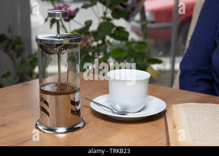 Winter tee Konzept. Frau Hände. Mädchen gießt Zitrusfrüchte Tee mit Zitronen und Orangen aus transparentem Glas Teekanne in eine Tasse. Stockfoto