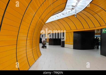 Eine junge Frau, Mutter, mit einem Baby Stroller geht hinunter einen Tunnel U-Bahnhof Marienplatz in München, Bayern, Deutschland Stockfoto