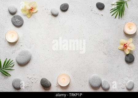 Spa-Konzept auf weißem Stein, Palm Blätter, Blumen, Kerzen und zen wie Graue Steine, Ansicht von oben, kopieren. Stockfoto