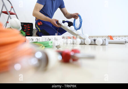 Elektriker am Arbeitsplatz installieren Lampe, mit Kabel in der Hand, Einbau der elektrischen Stromkreise, elektrische Verkabelung Stockfoto