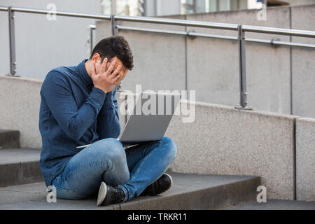 Betonte student bedeckte sein Gesicht die Vorbereitung auf eine Prüfung im Campus Bereich sitzen auf der Treppe. Student Mann Probleme mit Laptop, sitzen Stockfoto