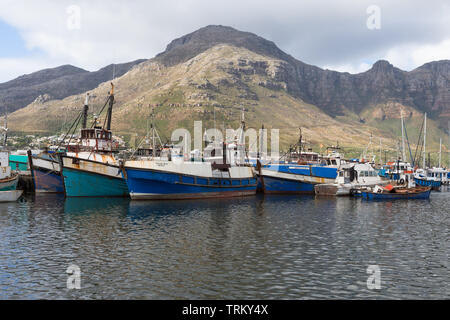 Hout Bay Harbour und bunten kommerzielle Fischerei Boote oder Schiffe, die vor dem Hintergrund der Berge in Kapstadt, Südafrika Stockfoto