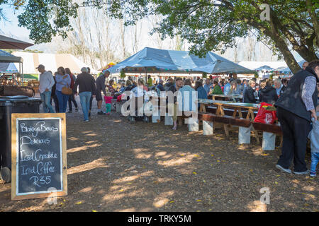 Im freien Markt Veranstaltungsort mit Menschen und Touristen an den Bänken und Tischen und Stühlen sitzen unter Bäumen am Blaauwklippen Wine Estate, Stellenbosch Stockfoto