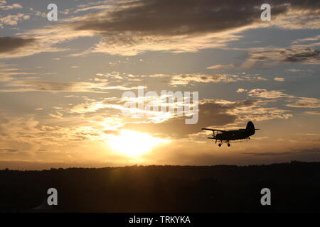 Antonov 2 oben am Himmel ein Sonnenuntergang fliegen. Stockfoto