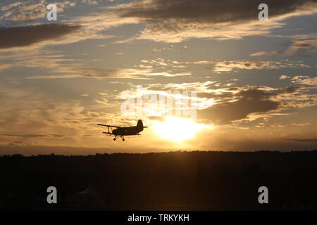 Antonov 2 oben am Himmel ein Sonnenuntergang fliegen. Stockfoto