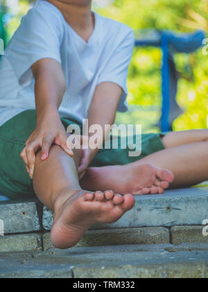 Kind Junge fühlen Knieschmerzen nach Spielen. gesund problem Konzept. Stockfoto