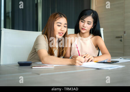 Zwei asiatische Geschäftsfrau Kollegen nebeneinander stehen in einem Büro. Sie geschäftsfrau sprechen über Bericht in Dateien. Stockfoto