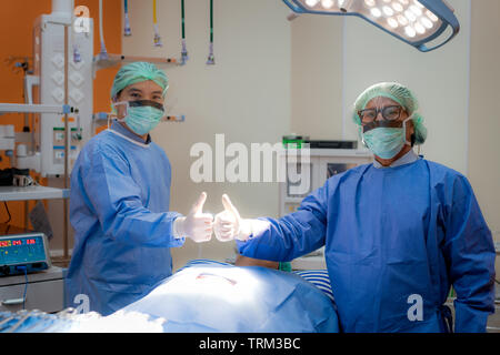 Chirurgen Team angebaut in Uniform und Maske zeigen thump bis in den Operationssaal. Op-Team die Vorbereitung für die Chirurgie in Betrieb. Stockfoto