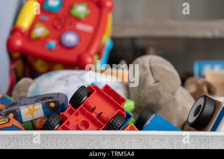 Nahaufnahme von einer Box von Spielzeug, mit vielen verschiedenen Objekten einschließlich Soft Spielzeug, Spielen, Autos und Kleinkind Spielzeug. Stockfoto
