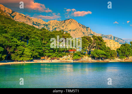 Fantastische Sommerferien und der Lage am Strand. Herrliche Kiesstrand mit hohen Bergen im Hintergrund bei Sonnenuntergang, Brela, Makarska Riviera, Dalmatien, Cr Stockfoto