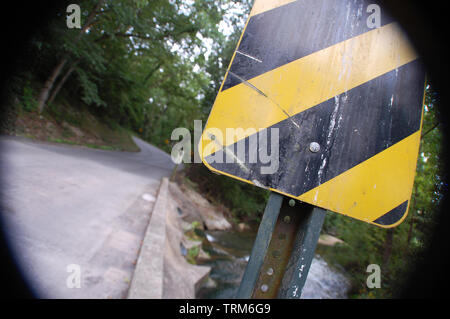 Eine Vorsicht Schild auf eine windige Landstraße. Stockfoto