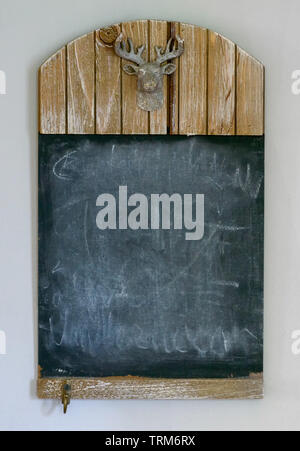 Leer Landhausstil Schiefertafel mit Kopieren und Schnitzen der Kopf einer Hirsche mit geweihen auf einer weißen Wand Stockfoto