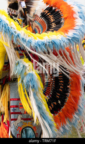 Nahaufnahme eines orange, blaue, gelbe und weiße Feder und Federkiel Kopfschmuck und Hektik getragen von einem phantastischen Tänzer bei einem Pow Wow. Stockfoto