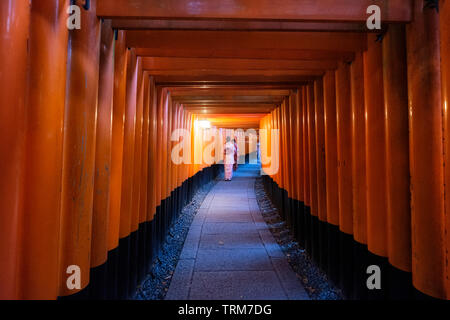 Frau gekleidet Kimono zu Fuß in roten alten Holz torii Tor an Fushimi Inari Schrein in Kyoto, Japan Stockfoto