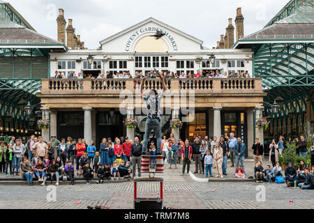 Street-Performer, der eine Menge in Covent Garden, London, England, unterhält. Stockfoto