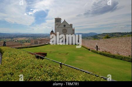 Malerischer Blick auf Basilika di San Francesco d'Assisi Fassade, die alten Mauern und den vorderen Garten Stockfoto