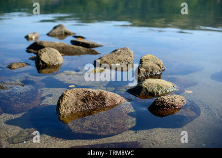 Nassen Kieselsteinen am Strand in der Abendsonne. Sea Wave auf Seeküste mit runden Steinen. Stockfoto