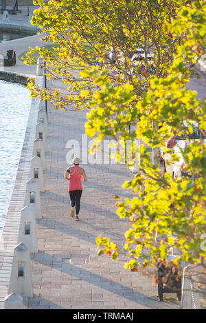 Eine Frau joggt neben Claisebrook Cove, East Perth, Western Australia. Stockfoto