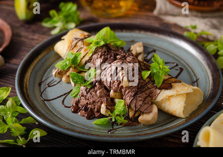 Schönen Dessert mit hausgemachten Schokoladeneis, Basilikumblätter und Banane, gekrönt mit dunkler Schokolade Stockfoto