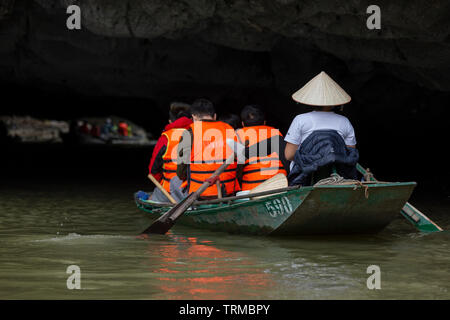 NINH BINH, VIETNAM - Februar 2019; Touristen in Ruderbooten Pass durch eine Höhle in der Tam Coc Stockfoto