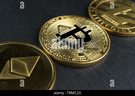 Physische Bitcoin, Litecoin und des Astraleums Gold Münzen auf einen schwarzen Stein Schiefer platte Hintergrund. Cryptocurrency. Geringe Tiefenschärfe. Stockfoto