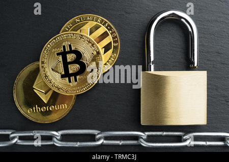 Physische Bitcoin, Litecoin und des Astraleums Gold Münzen auf einen schwarzen Stein Schiefer Platte mit Kette. Cryptocurrency blockchain abstraktes Konzept. Stockfoto