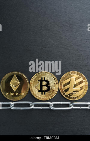 Physische Bitcoin, Litecoin und des Astraleums Gold Münzen auf einen schwarzen Stein Schiefer Platte mit Kette. Cryptocurrency blockchain abstraktes Konzept. Stockfoto