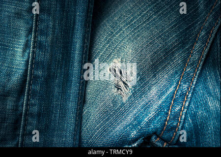 Ausgefranste Loch auf der Rückseite des alten blauen Jeans mit Doppelnähten. Denim Jeans Hintergrund. Stockfoto