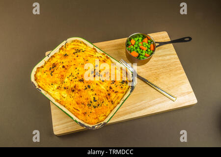 Hirten oder Cottage Pie in Schüssel mit Möhren und Erbsen serviert. Stockfoto