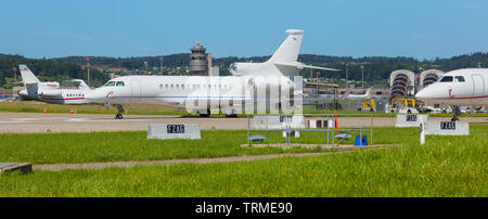 Kloten, Schweiz - 8. Juni 2019: Flugzeuge am Flughafen Zürich, eine Dassault Falcon 7X, im Vordergrund. Die Dassault Falcon 7X ist eine große Kabine busi Stockfoto