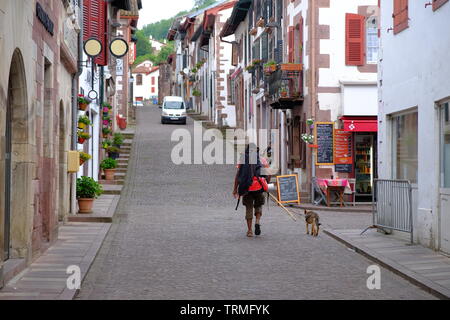 Pilger mit einem Hund früh morgens auf dem Weg nach Santiago auf dem Weg von St. James, Straßen von st-jean-Pied-de-Port, Frankreich, Juni 2019 Stockfoto