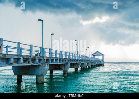 Lange pier Position am Meer unter der blauen bewölkten Himmel Stockfoto