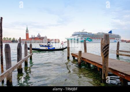 Ein grosses Kreuzfahrtschiff in Venedig segeln durch San Giorgio Maggiore von der Waterfront mit einer Gondel im Vordergrund, Italien Europa EU Stockfoto