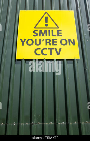 Lächeln Sie auf CCTV-freundliche Anfrage Zeichen auf industrielle Einheit DE Stockfoto