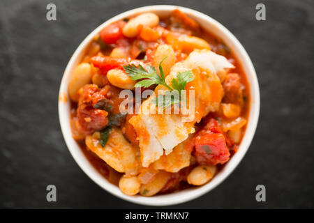 Ein Pollack und Chorizo Wurst fisch Eintopf mit Tomaten, geröstete Paprika, Tomaten aus der Dose, gehackte Zwiebeln, cannellini Bohnen und Petersilie. T Stockfoto