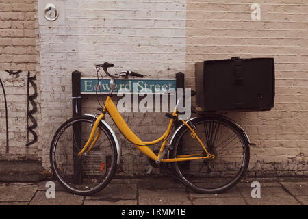 Alten retro Gelb bicecle Park neben dem Straßenschild. Stockfoto