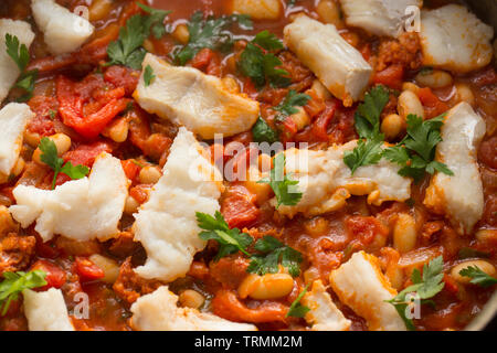 Ein Pollack und Chorizo Wurst fisch Eintopf mit Tomaten, geröstete Paprika, Tomaten aus der Dose, gehackte Zwiebeln, cannellini Bohnen und Petersilie. T Stockfoto