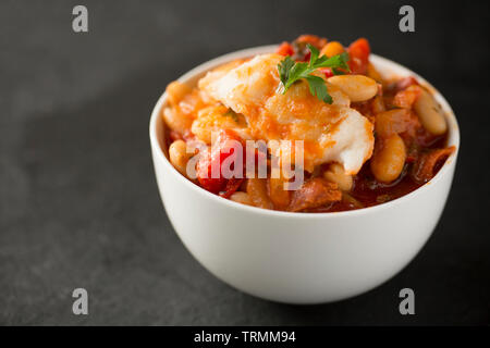 Ein Pollack und Chorizo Wurst fisch Eintopf mit Tomaten, geröstete Paprika, Tomaten aus der Dose, gehackte Zwiebeln, cannellini Bohnen und Petersilie. T Stockfoto