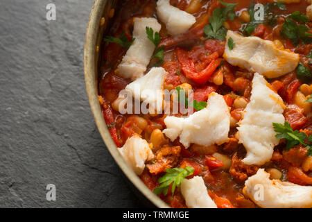 Ein Pollack und Chorizo Wurst fisch Eintopf mit Tomaten, geröstete Paprika, Tomaten aus der Dose, gehackte Zwiebeln, cannellini Bohnen und Petersilie. T Stockfoto