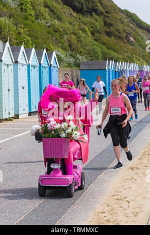 Bournemouth, Dorset, Großbritannien. 9. Juni 2019. Tausende beteiligen sich an Rennen für das Leben in Bournemouth Teil in 10k oder 5k zu nehmen. Cancer Research UK ist zum ersten Mal lädt alle zum Mitmachen ein und vereint in einem gemeinsamen verursachen Krebs zu schlagen. Die Teilnehmer nehmen an den 10k-Fall zusammen Bournemouth Seafront, um zu helfen, Kapital für Krebs schlagen Forschung anzuheben. Dame in rosa, pink Mobility Scooter mit Blumen geschmückt. Credit: Carolyn Jenkins/Alamy leben Nachrichten Stockfoto