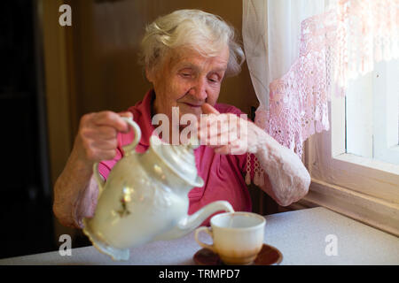 Großmutter. Ältere Frau mit tiefen Falten in ihrem Haus in der Küche. Stockfoto