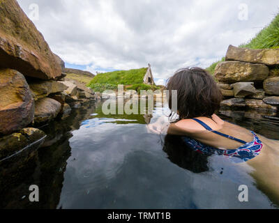 Frau baden und entspannen in einer kleinen Hot Spring Pool in Hrunalaug, Island Stockfoto