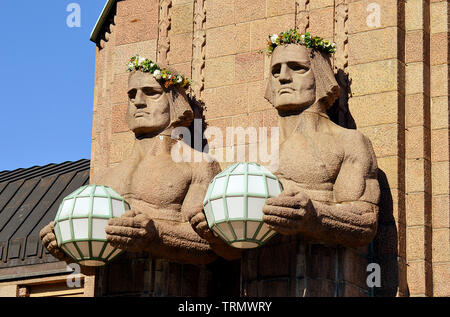 HELSINKI, Finnland - 6 April 2019: Zwei der steinernen Wächter verwendet Lichter am Haupteingang Eliel Saarinen Hauptbahnhof zu unterstützen. Stockfoto