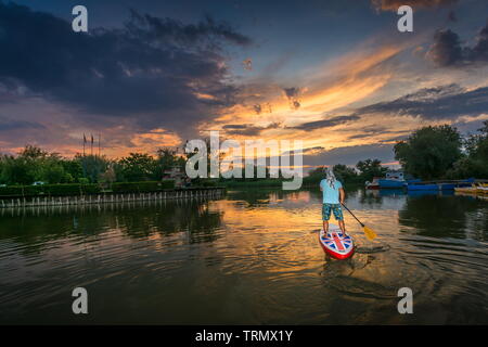 Gura Portitei, Rumänien - 08 Juni 2019: der Mensch auf dem SUP board, Stand Up Paddling bei Sonnenuntergang auf dem See im Donaudelta in Gura Portitei, Rumänien Stockfoto