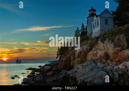 Bass Harbor Head Lighthouse und Segel Yacht bei Sonnenuntergang in Acadia National Park, Maine Stockfoto