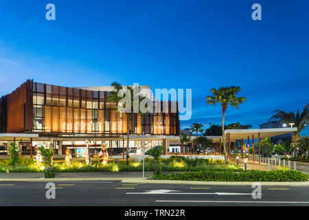 Die Fassade der Cairns Performing Arts Center in der Dämmerung beleuchtet. Eine Reihe von "bagu "heimischen Skulpturen sitzen an der Vorderseite des Zentrums. Cairn Stockfoto